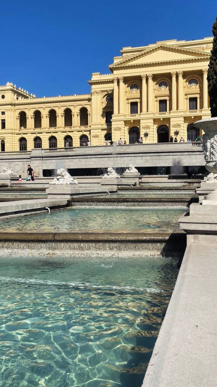 Palácio neoclássico amarelo em Buenos Aires com piscina e fonte em primeiro plano